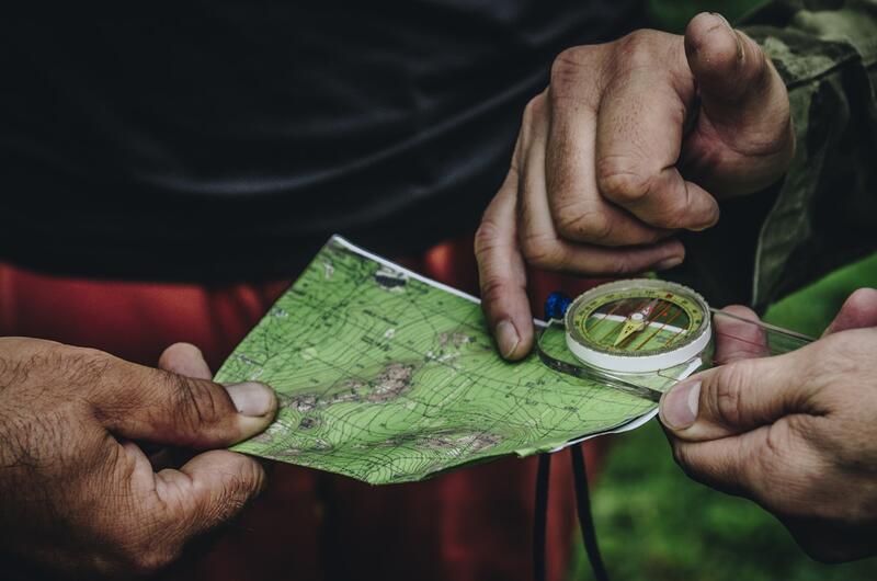 Two people using a map and compass in the woods